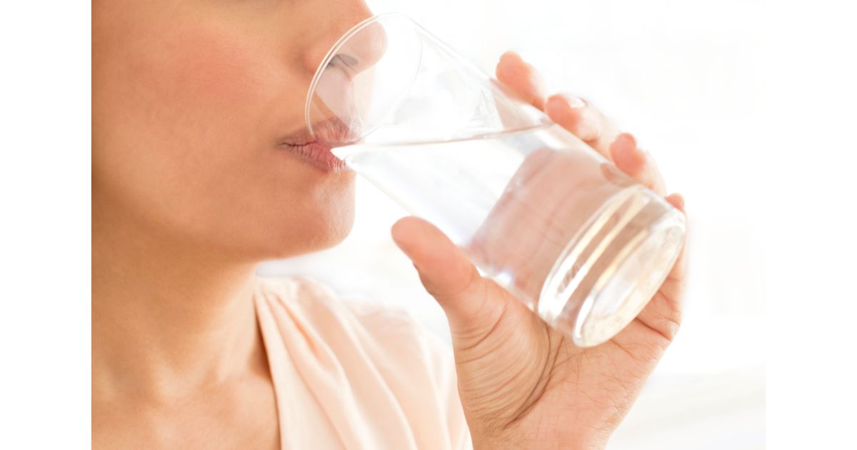 A close-up of a person drinking water from a glass, focusing on the act of hydration.