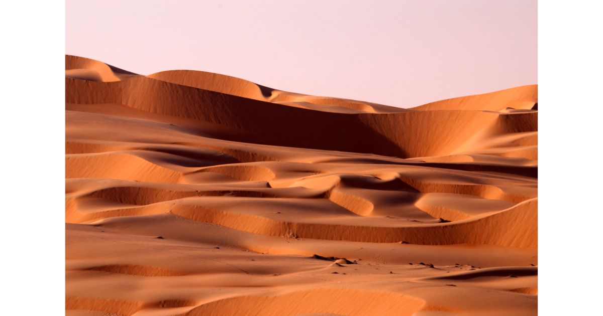A beautiful view of the vast desert landscape with rippling sand dunes, illuminated by soft, warm light.