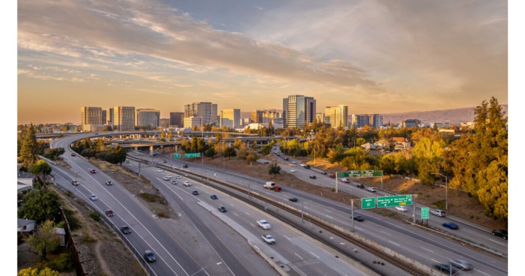 A scenic view of San Jose's skyline with highways and traffic, framed by modern buildings and surrounding greenery.