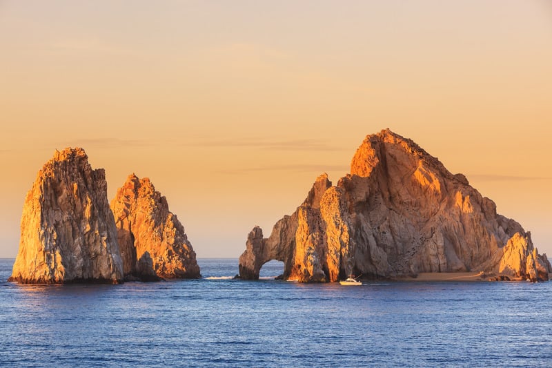 The iconic Land’s End rock formations at Cabo San Lucas, Mexico, bathed in warm sunset light with the ocean in the foreground.