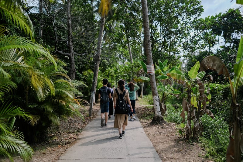 A group of eco-tourists walking along a paved path through lush greenery and tropical plants in Playa Hermosa.