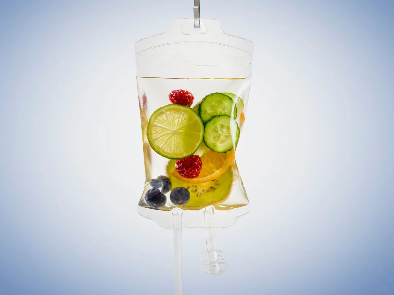IV drip bag filled with clear liquid and fresh fruits like lime, cucumber, berries, and orange slices, symbolizing hydration and nutrient infusion.