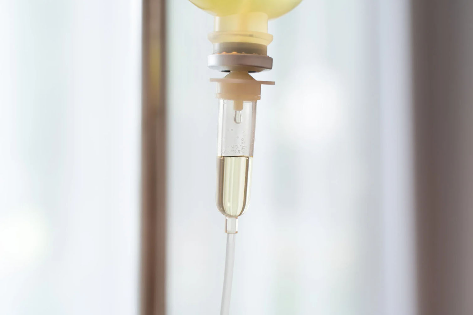 Close-up of an intravenous (IV) drip with clear liquid flowing through the tubing.