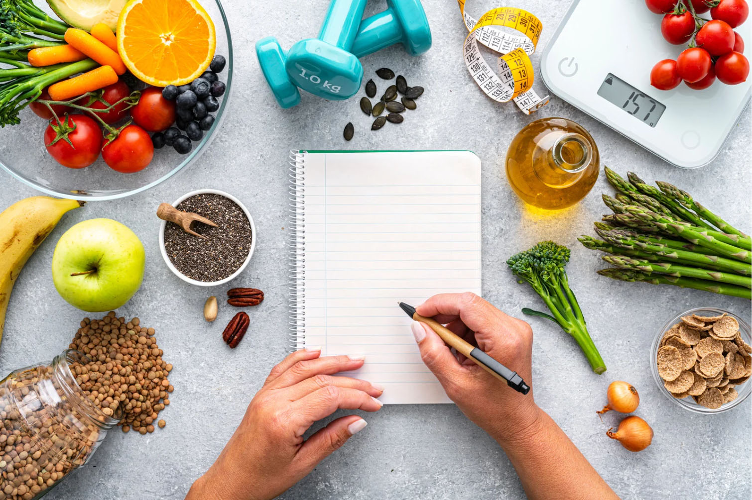 A healthy lifestyle setup featuring fresh fruits, vegetables, seeds, and a scale, with a notebook and pen ready for planning, symbolizing wellness and fitness tracking.