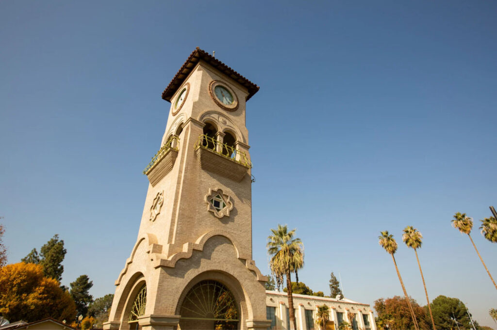 The historic Bakersfield Clock Tower under a clear blue sky with palm trees surrounding it, showcasing the city's iconic architecture.