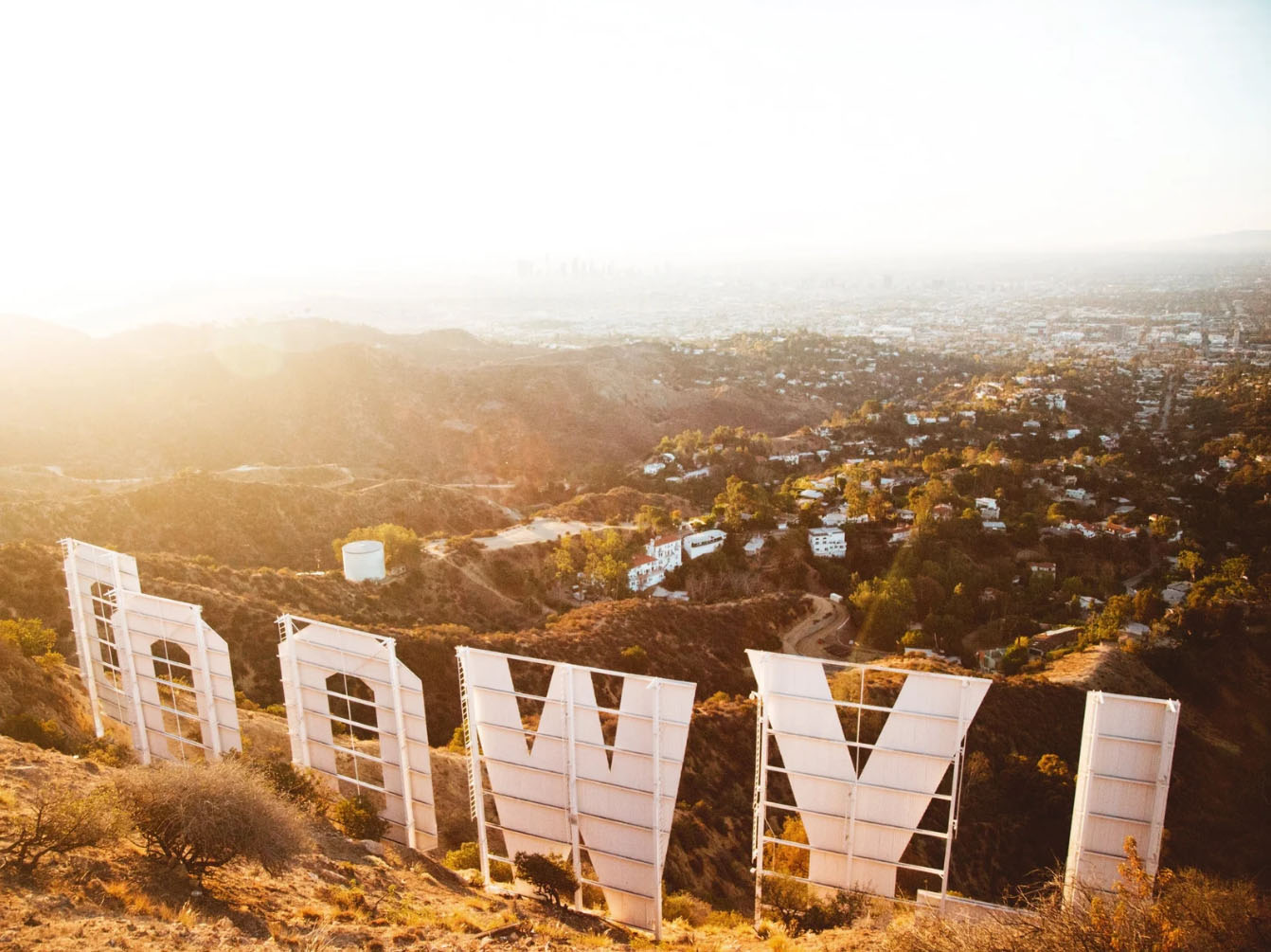 A view of the iconic Hollywood sign at sunset, with the sprawling city of Los Angeles visible in the background, showcasing the natural beauty of the area.