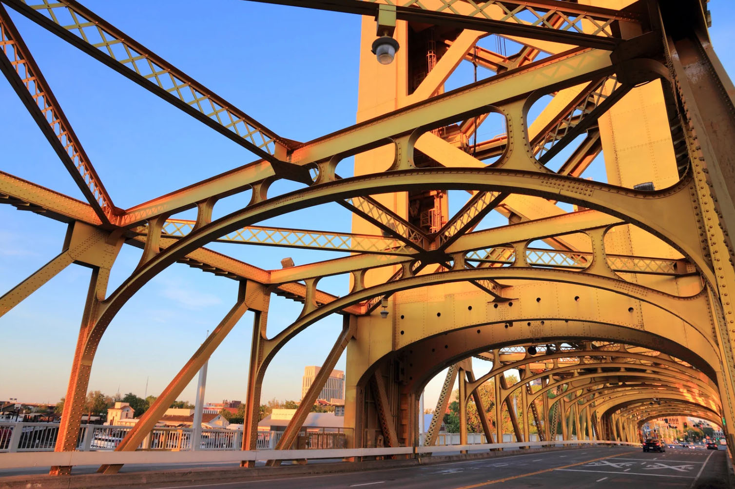 A close-up view of the iconic Tower Bridge in Sacramento, with intricate metalwork illuminated by the golden light of sunset, showcasing its architectural details.