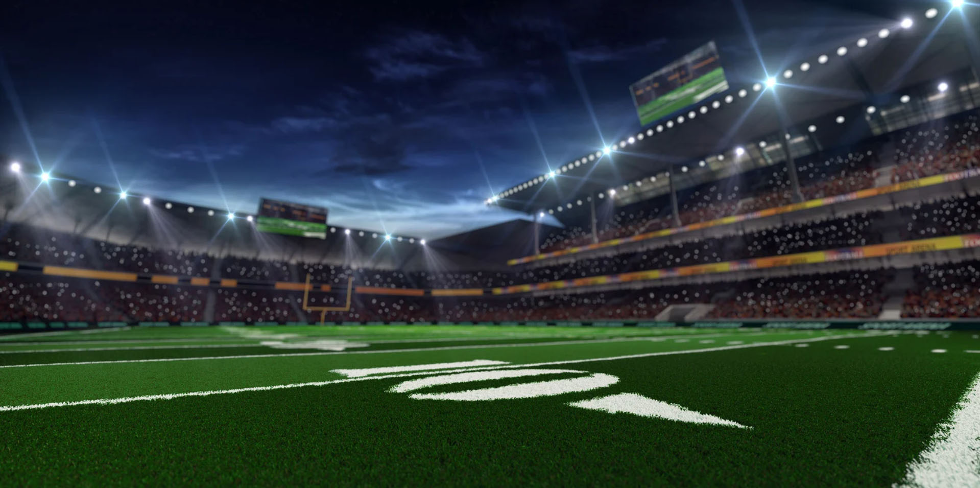 View of an empty football stadium with bright lights and a close-up of the field, showcasing the 50-yard line markings on the turf under a dramatic sky.